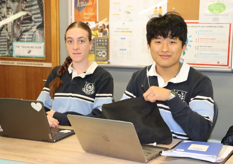 Students seated at a table, with laptops in front of them.