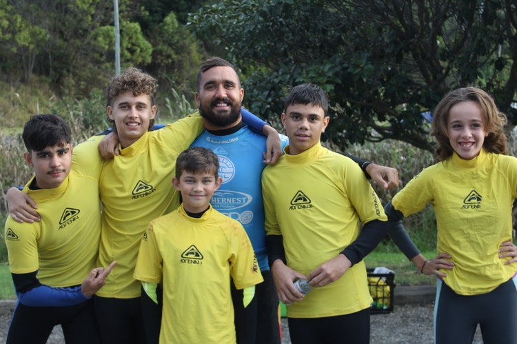 Image of students and mentor in yellow rashies, happily grouped together.